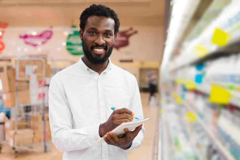 Smiling Nigerian shop owner taking inventory in a retail store